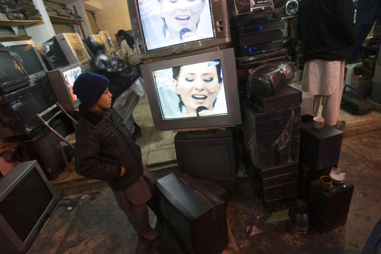 Image: An Afghan boy watches television at a television and satellite shopping centre in Herat